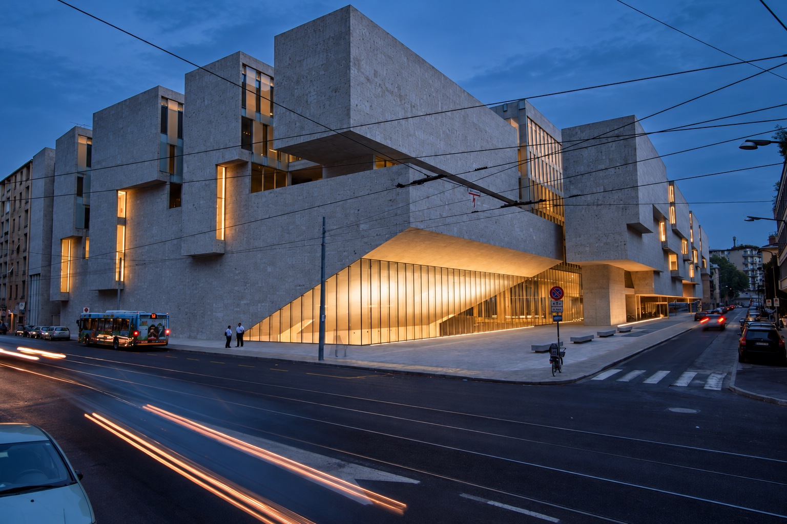 Photograph of the Röntgen building at dusk, with its sculptural stone façade and illuminated Aula Magna.